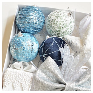 Macro detail of blue velvet and silver glitter Christmas ornaments in a white gift box