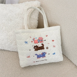 Close-up of white quilted tote bag featuring cat embroidery and silk ribbon details