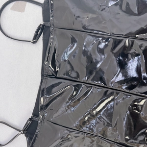 Détail de la robe en similicuir noir montrant les bretelles réglables et les coutures