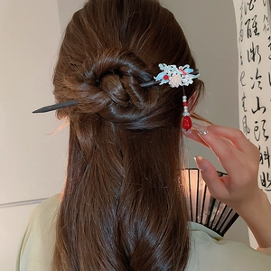 Close-up of hair stick with butterfly flower charms and beaded tassel on model