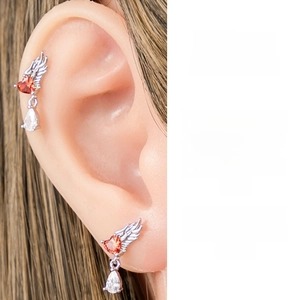 Detail showing titanium steel angel wing ear stud with red heart gem and water drop pendant