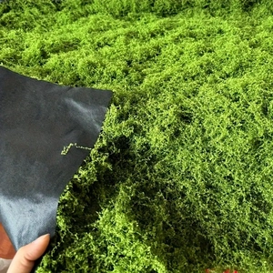 Close-up of artificial green moss lawn with textured synthetic fibers and black backing