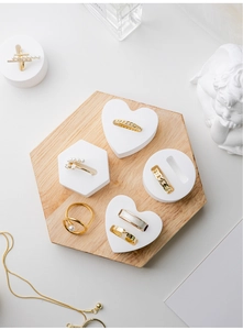 Detail of gold rings and necklace displayed on white geometric jewelry stands