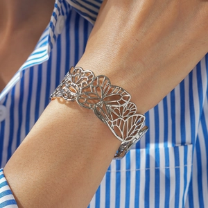 Détail d'un bracelet manchette ouvert avec un motif floral évidé très complexe