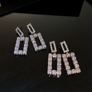 Detailed view of silver and gold geometric hollow earrings with sparkling square zircons