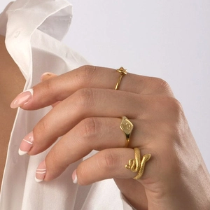 Three-piece stackable gold snake ring set with signet and band on female hand