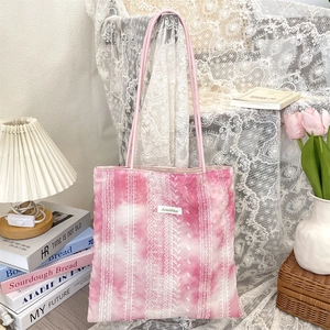 Detail of pink tie-dye tote bag with white lace embroidery and brand label on front