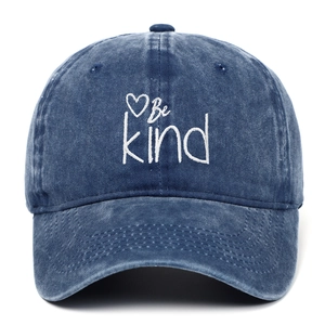 Detailed view of white Be Kind embroidery and heart on navy washed cotton baseball cap