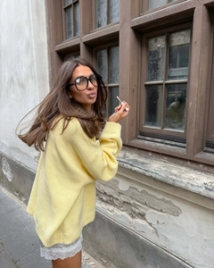 Close-up of bright yellow oversized knit sweater with black frames and lipstick details
