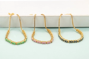Golden box chain bracelets with green, pink, and black evil eye charms in a set