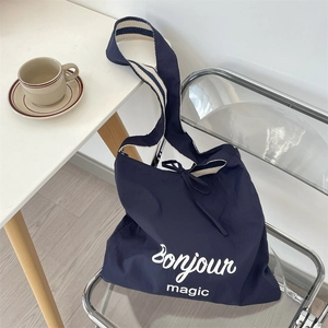 Detail of navy canvas tote bag with Bonjour print and striped woven shoulder strap