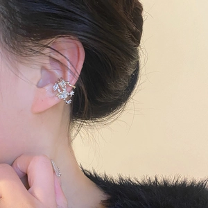 Close-up of elegant silver flower ear cuff with zircon stones worn on the ear bone