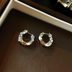 Macro shot of silver lava texture hoop earrings on dark brown leather jewelry case