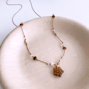 Detailed shot of star tiger eye pendant with beaded gravel necklace in ceramic bowl