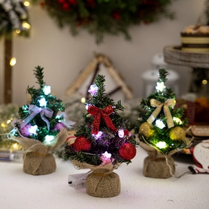 Close-up of three mini tabletop Christmas trees with LED lights and burlap base