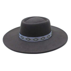 Detail of dark grey wool felt boater hat featuring a blue geometric embroidered band
