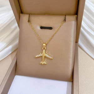Macro detail of gold airplane pendant with pave crystals on silk jewelry box