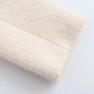 Detailed macro view of warm beige faux shearling fabric texture for winter coats