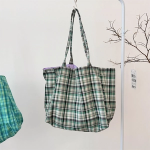 Detail of green plaid canvas tote bag with spacious purple interior and long strap