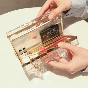 Acryl-Clutch mit Wellenmuster, Goldbeschlägen und Kette, zeigt das Innenraumvolumen