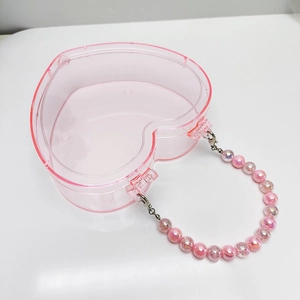 Detailansicht der herzförmigen transparenten Kunststoff-Schmuckschatulle mit rosa Perlengriff