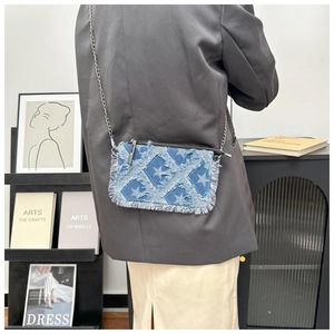 Detail of denim crossbody bag with star pattern and silver chain on a model