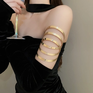 Close-up of a layered gold arm cuff with hammered and polished textures on a model