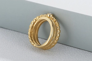 Detail of a vintage gold stainless steel ring with beaded texture and single zircon