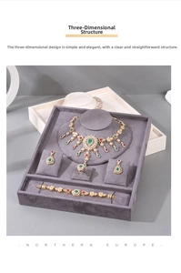 Detail of vintage jewelry set with red and green gems on a grey velvet display tray