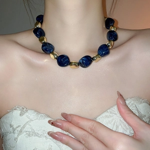 Detail of blue marble acrylic beads and golden links on a vintage choker necklace