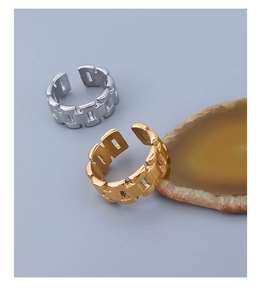 Detail of gold and silver chunky chain rings on a natural stone slice display