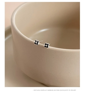 Macro view of black four-leaf clover stud earrings with polished silver edges