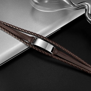 Detailed view of brown braided leather bracelet with blank metal plate on modern background