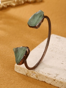 Detail of adjustable bronze spiral cuff featuring raw translucent green fluorite stones