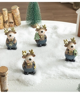 Detailed macro view of four resin reindeer figurines with golden antlers on snowy wood logs