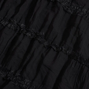 Detail of black pleated fabric texture with delicate lace trim on backless dress