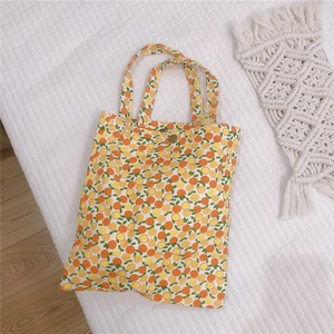 Détail du mini sac en toile avec imprimé orange et fermeture par bouton pression en métal