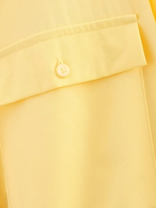 Close-up of pocket flap and button on yellow twill fabric with double stitching detail