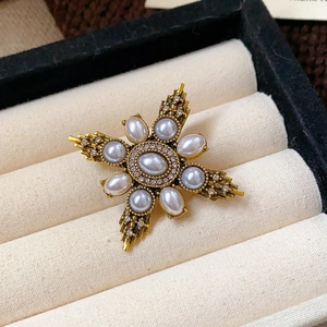 Macro shot of vintage star brooch with rhinestones and faux pearls in beige jewelry box