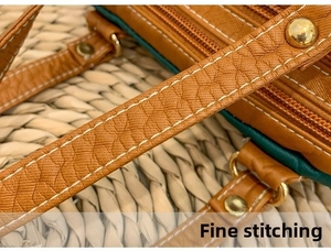 Close-up of brown pebbled leather texture with fine stitching and gold hardware detail
