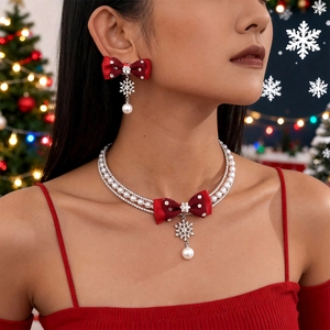 Detail of Christmas necklace with red bow, pearls, and sparkling snowflake pendant
