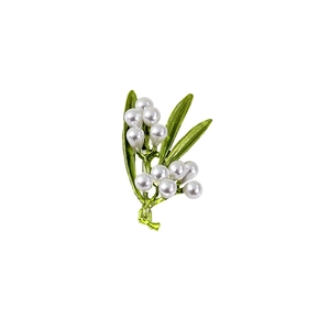 Macro shot of lily of the valley brooch with green leaves and white pearls details