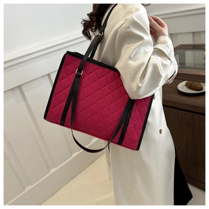 Model wearing a large quilted tote bag in fuchsia pink with black shoulder straps