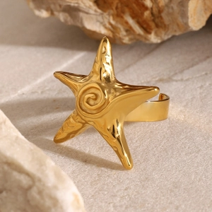 Detailed close-up of a 18k gold starfish open ring on a natural rock background
