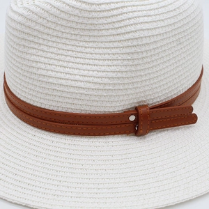 Détail d'un chapeau de paille blanc avec bande en similicuir brun et rivets