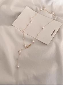 Detailed Y-shaped pearl necklace featuring white round pearls on a delicate gold chain link