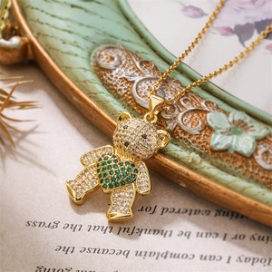 Gros plan du pendentif ours doré avec des zircons blancs et verts sur un collier