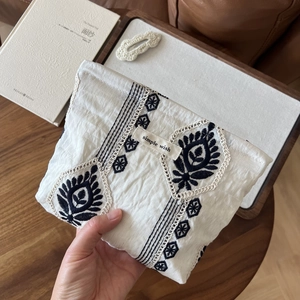 Close-up of linen makeup bag with ethnic embroidery and simple wish label