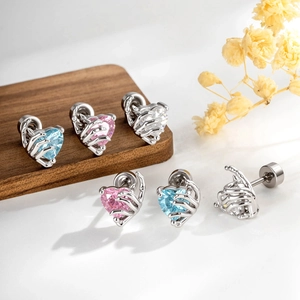 Boucles d'oreilles en argent en forme de main avec zircons cœur sur socle en bois