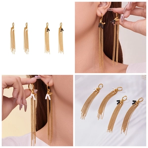 Macro detail of 18k gold plated stainless steel long tassel earrings with letter pendants